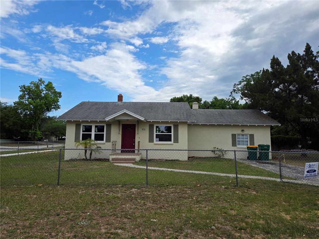 A single-story house with a red front door and a chain-link fence in front — 101 E ATWATER AVENUE, EUSTIS, FL