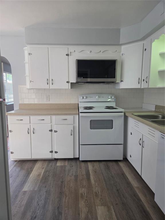 A kitchen with white cabinets, a white stove, a microwave, and wood-look flooring — 101 E ATWATER AVENUE, EUSTIS, FL