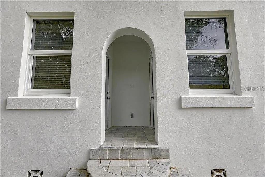 An arched entryway with tiled steps is flanked by two windows on a white wall — 1862 6TH STREET, SARASOTA, FL