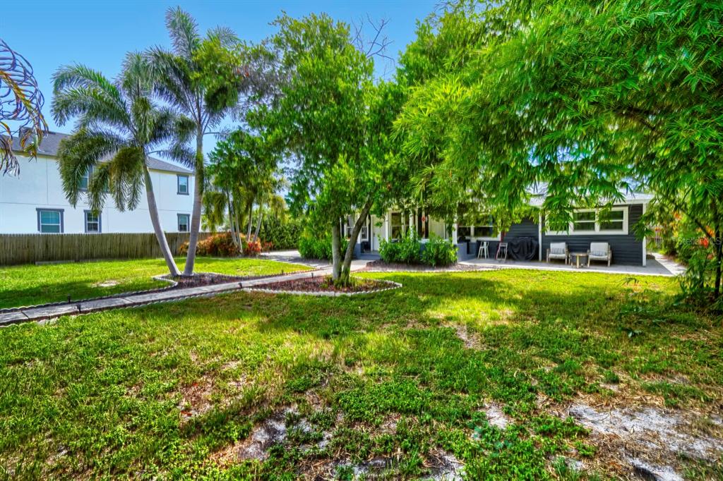 A backyard with a grassy lawn, palm trees, and a patio attached to a house — 940 25TH STREET N, ST PETERSBURG, FL