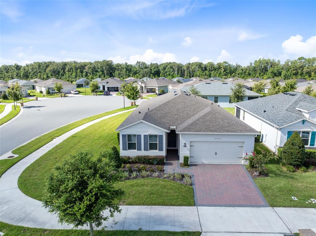 An aerial view shows a single-story suburban house with a brick driveway and gray roof — 17782 BLAZING STAR CIRCLE, CLERMONT, FL