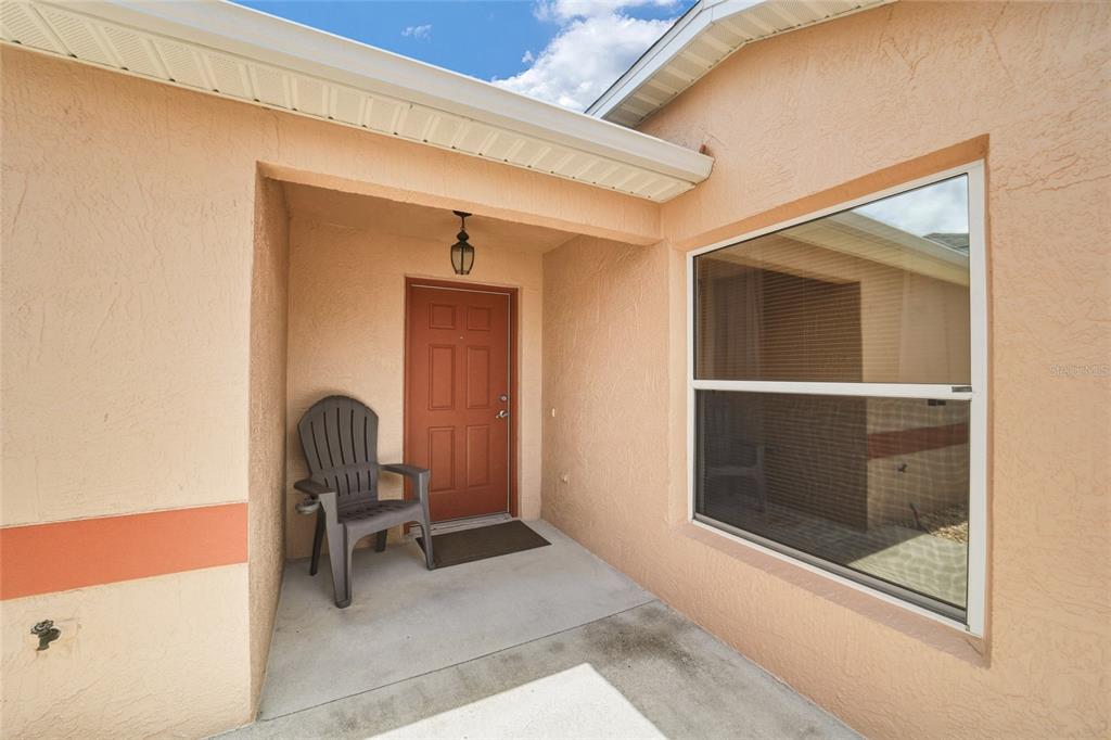 A front entryway features a red door, a gray chair, and a large window — 308 ALMERIA STREET, THE VILLAGES, FL