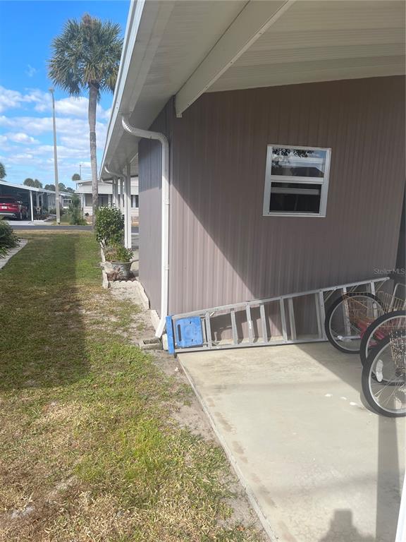The exterior of a home features vertical siding, a gutter, a window, and a ladder — 4179 ROLLING OAKS DRIVE, WINTER HAVEN, FL