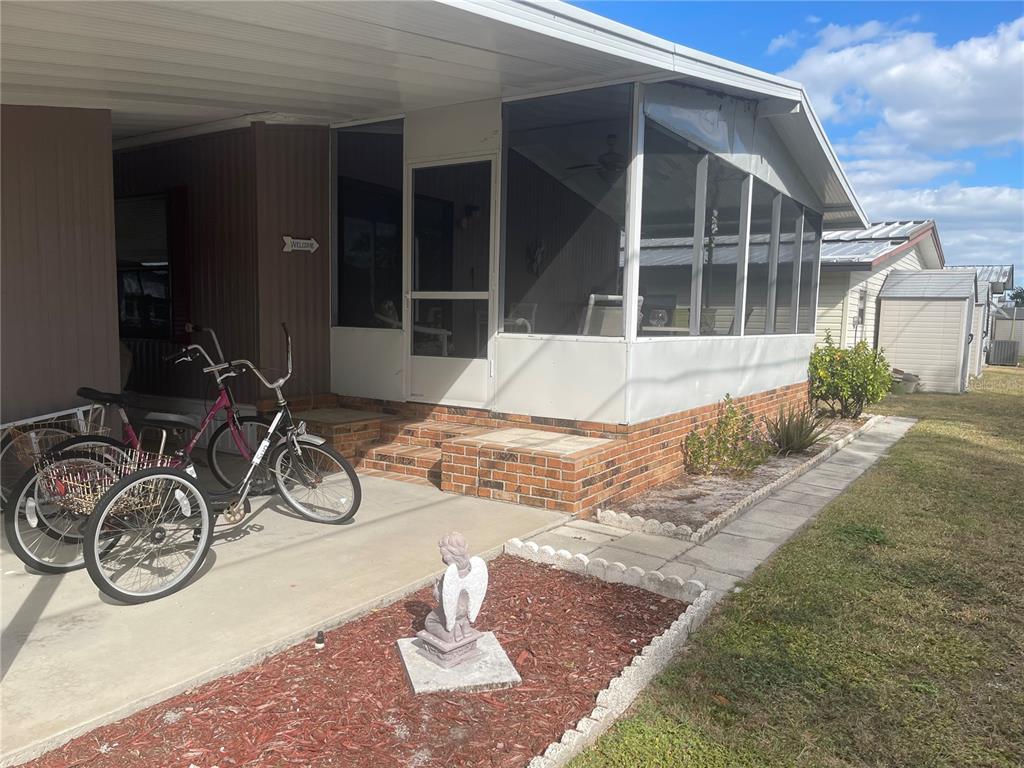 A mobile home exterior features a screened porch, brick skirting, and a concrete driveway — 4179 ROLLING OAKS DRIVE, WINTER HAVEN, FL