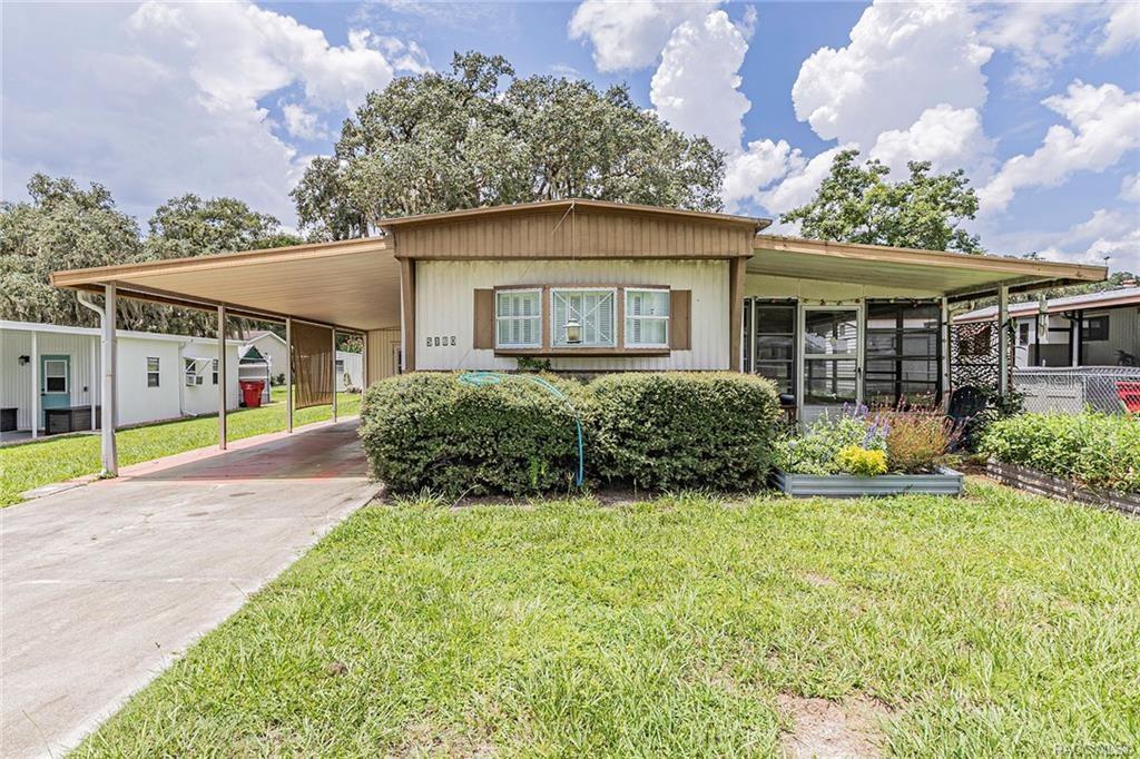 A single-story mobile home with a carport, a front lawn, and a large central window — 5160 S FLORENCE TERRACE, FLORAL CITY, FL