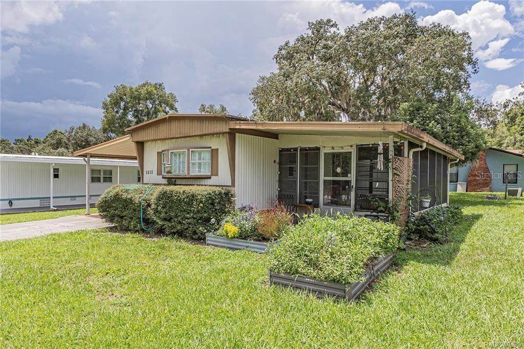 A single-story mobile home with a screened-in porch, metal roof, and a front garden bed — 5160 S FLORENCE TERRACE, FLORAL CITY, FL