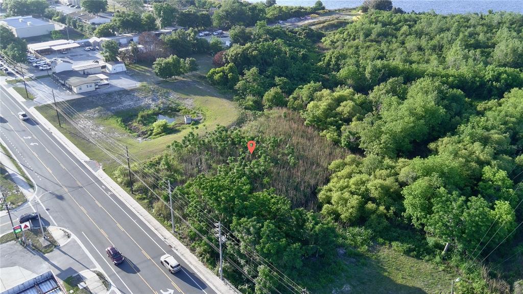 An aerial view shows a vacant, tree-covered lot next to a road and a building — DUNDEE ROAD, WINTER HAVEN, FL