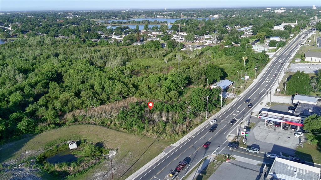An aerial view shows a vacant, tree-covered lot next to a road and a gas station — DUNDEE ROAD, WINTER HAVEN, FL