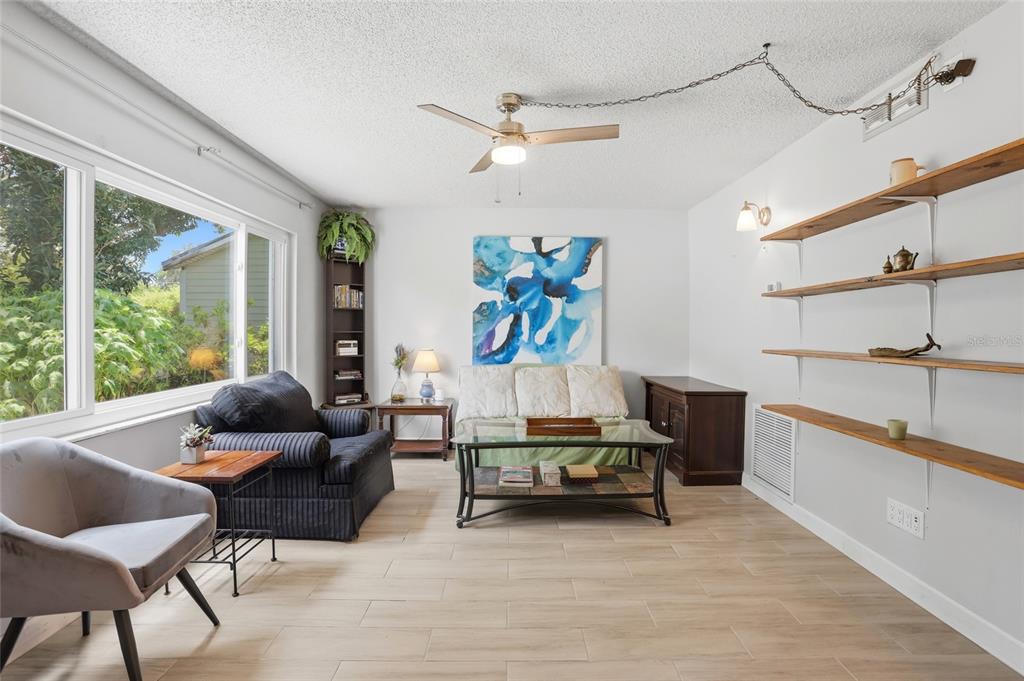 A screened-in porch features a glass-top table, chairs, and a view of a backyard garden — 804 ROSALIA DRIVE, SANFORD, FL