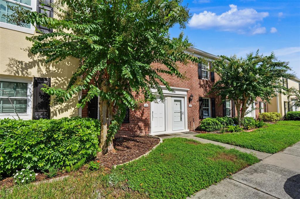 A two-story brick and stucco townhouse exterior features a front entrance and landscaped yard — 13747 JUNIPER BLOSSOM DRIVE, TAMPA, FL