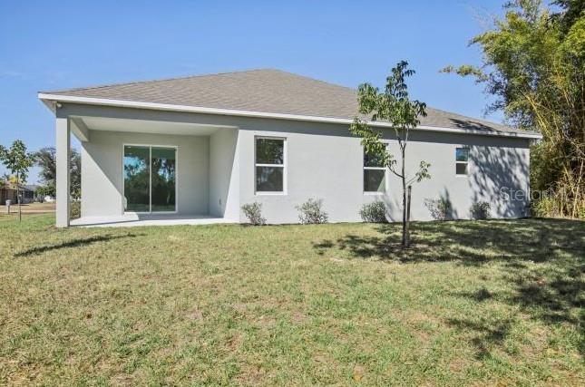 The exterior rear view of a single-story house features a covered patio and sliding doors — 2116 RIO DE JANEIRO AVENUE, PUNTA GORDA, FL