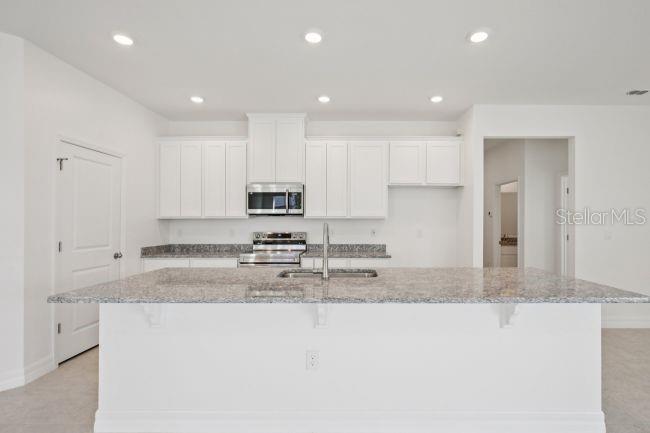 A kitchen with white cabinets, granite countertops, a large island, and stainless steel appliances — 2116 RIO DE JANEIRO AVENUE, PUNTA GORDA, FL