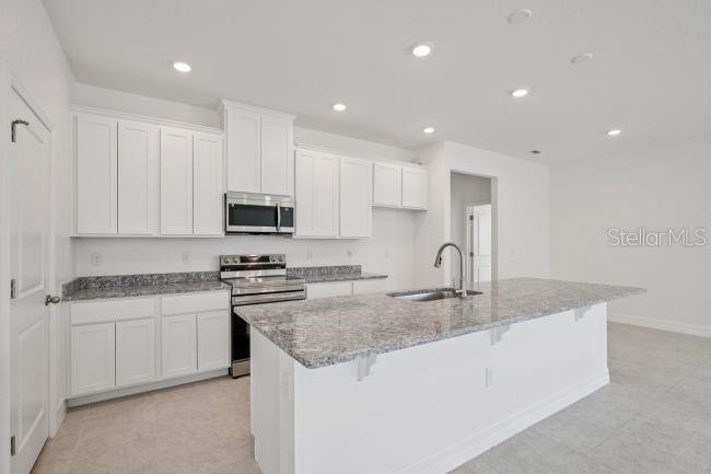 A kitchen features white cabinets, granite countertops, a center island, and stainless steel appliances — 2116 RIO DE JANEIRO AVENUE, PUNTA GORDA, FL