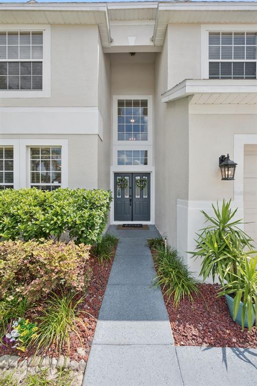 A concrete walkway leads to the dark double front doors of a two-story stucco home — 2563 WALNUT HEIGHTS ROAD, APOPKA, FL