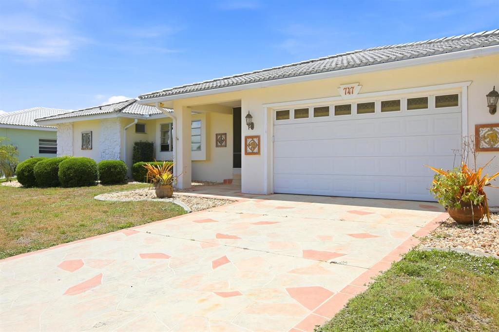 A single-story house with a white garage door, tiled roof, and a patterned stone driveway — 747 BAL HARBOR BOULEVARD, PUNTA GORDA, FL