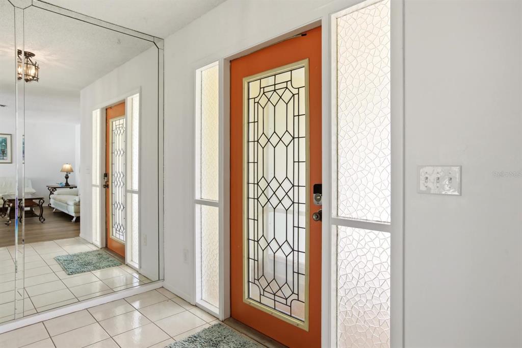 An entryway features a bright orange front door with decorative glass and side panels — 747 BAL HARBOR BOULEVARD, PUNTA GORDA, FL