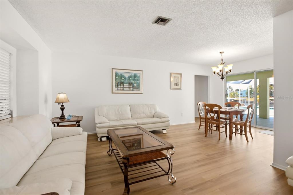 A living room and dining area with white sofas, a coffee table, and wood flooring — 747 BAL HARBOR BOULEVARD, PUNTA GORDA, FL
