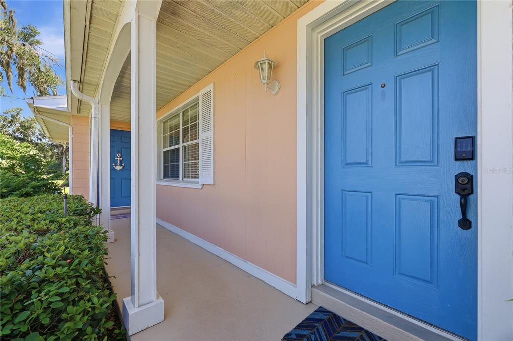 A bright blue front door opens onto a covered porch with peach-colored exterior walls — 936 N BAKER STREET, MOUNT DORA, FL