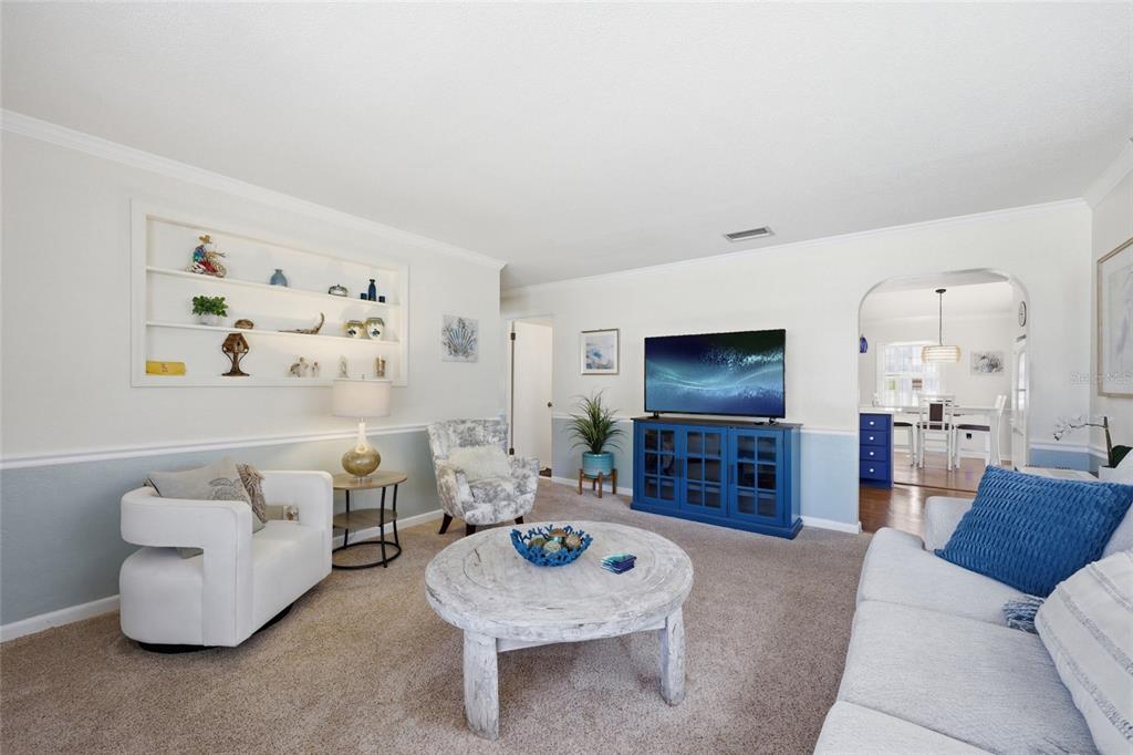 A living room features a white circular coffee table, blue media console, and built-in shelving — 936 N BAKER STREET, MOUNT DORA, FL