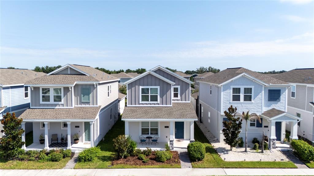 Three suburban houses with front porches stand side-by-side along a sidewalk under a clear sky — 2369 VOLUNTEER AVENUE, KISSIMMEE, FL