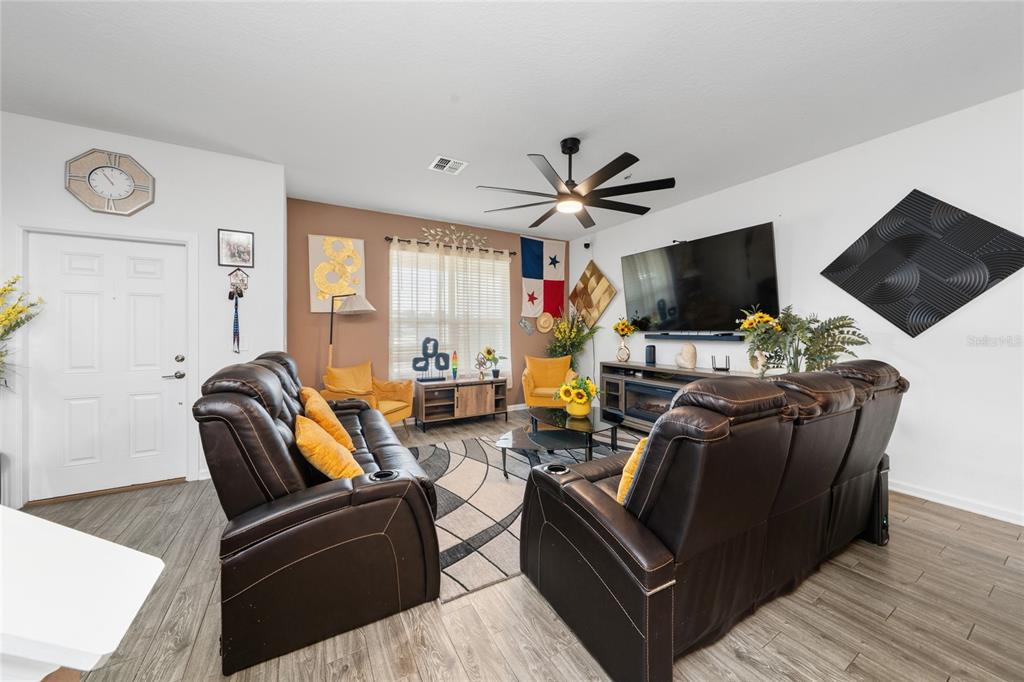 A living room features dark leather recliners, a large television, and a patterned area rug — 2369 VOLUNTEER AVENUE, KISSIMMEE, FL