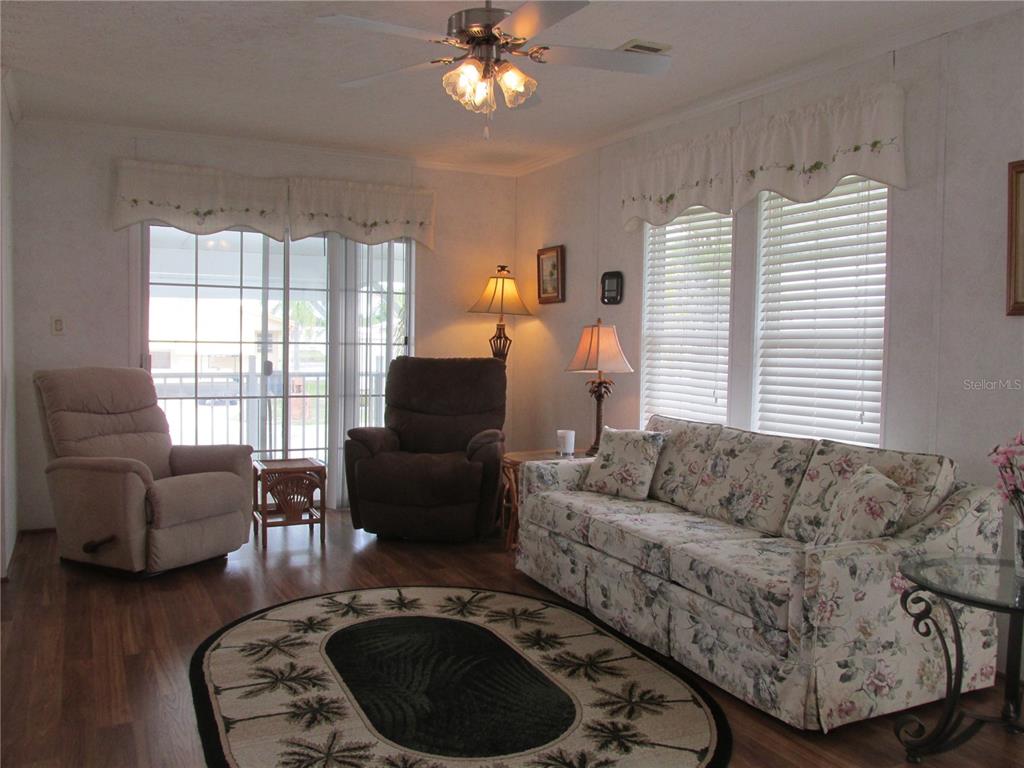 A living room features a floral sofa, two recliners, a ceiling fan, and sliding glass doors — 5 QUEEN OF WATERS STREET, LAKE WALES, FL