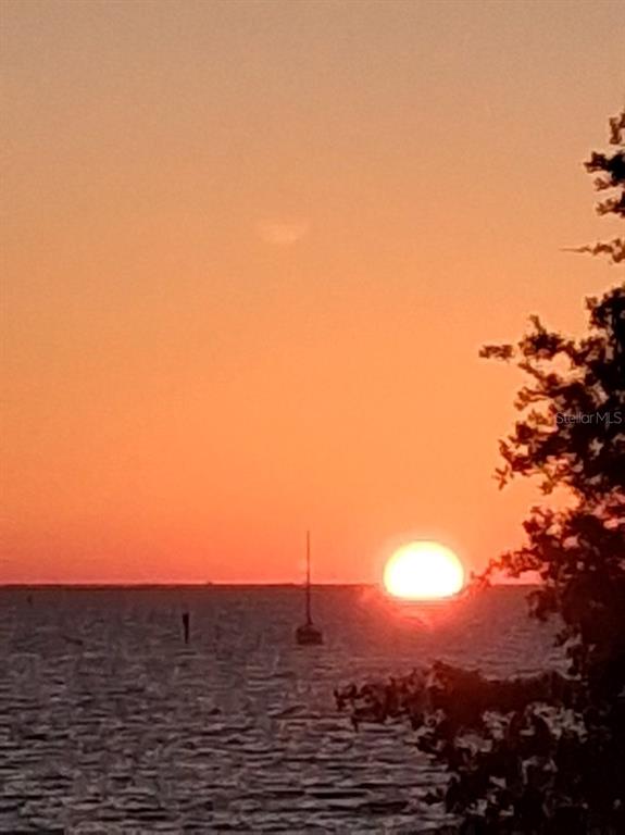A sunset view over the water with a sailboat silhouette and trees on the right — 611 B DESTINY DRIVE, RUSKIN, FL