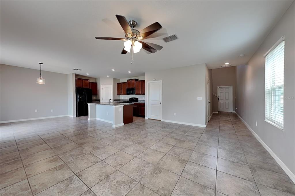 An open-concept kitchen and living area features tile flooring, dark wood cabinets, and a ceiling fan — 4906 WHITE CHICORY DRIVE, APOLLO BEACH, FL