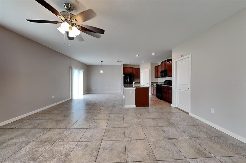 An open-concept living and kitchen area features tile flooring, a ceiling fan, and dark cabinetry — 4906 WHITE CHICORY DRIVE, APOLLO BEACH, FL