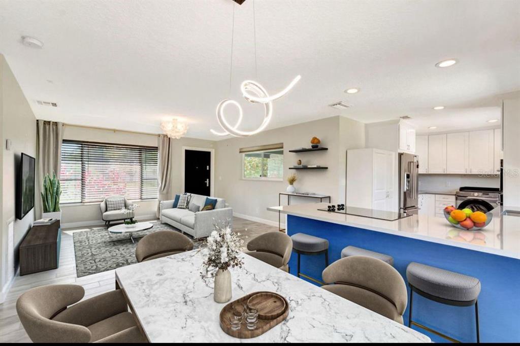 An open-concept living and dining area features a blue kitchen island and modern light fixtures — 125 SE 6TH AVENUE, BOYNTON BEACH, FL