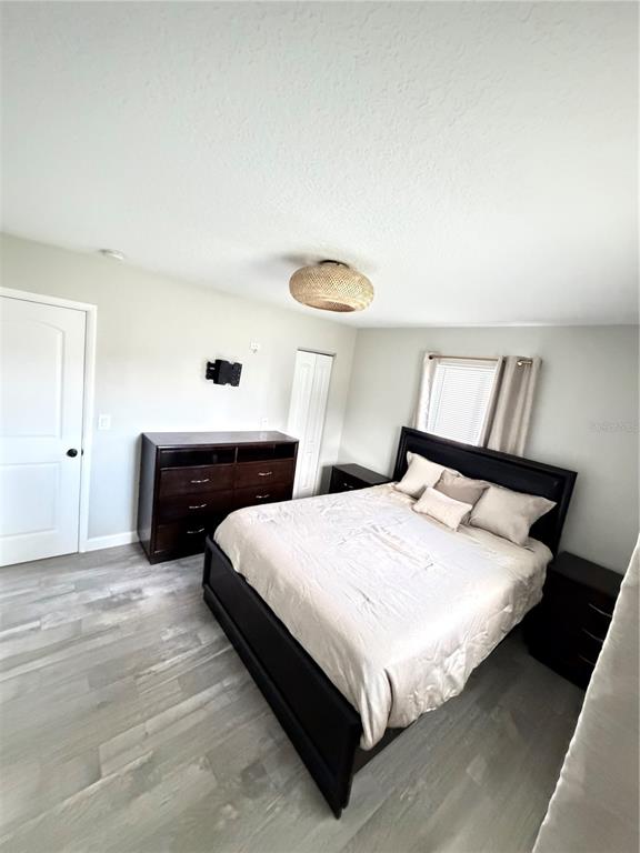 A bedroom features a dark wood bed frame, a matching dresser, and light-colored wood-look flooring — 125 SE 6TH AVENUE, BOYNTON BEACH, FL