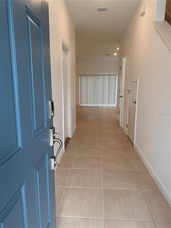 A view from an open blue front door into a tiled hallway with white walls — 2358 PARAVANE WAY, WESLEY CHAPEL, FL