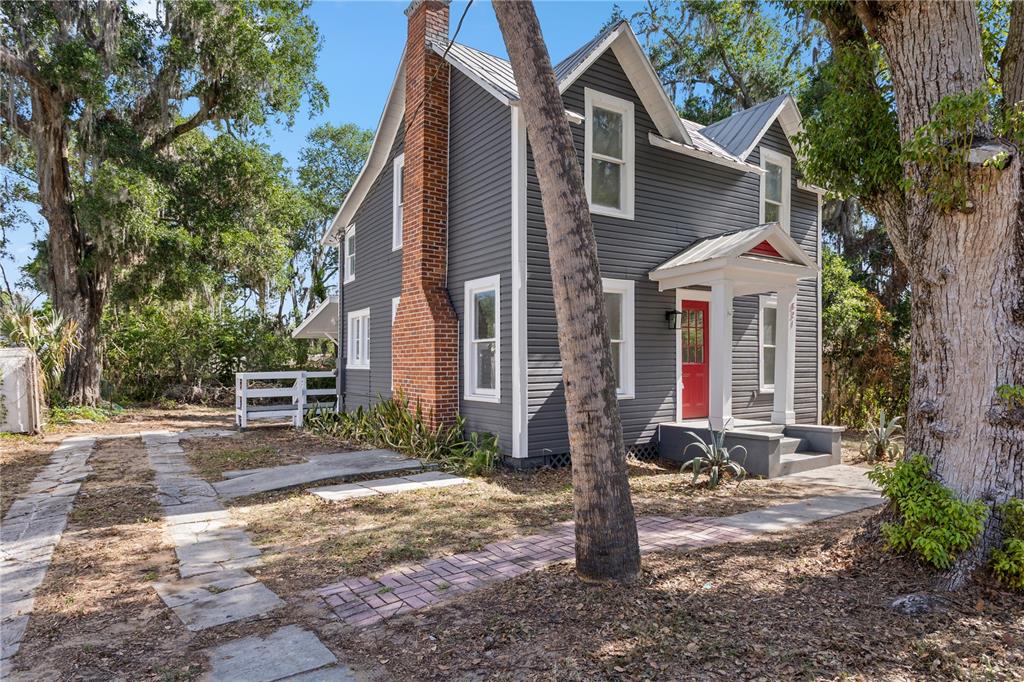 A two-story gray house with a red front door and a brick chimney — 821 E LEMON AVENUE, EUSTIS, FL