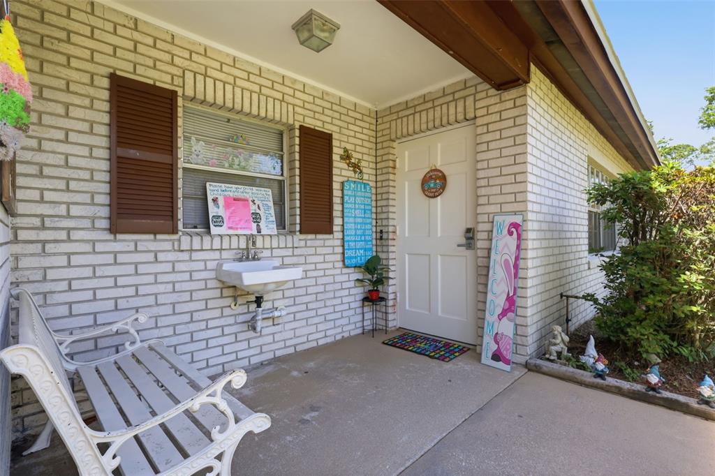A white brick exterior entrance features a sink, a bench, and a welcome sign — 601 N PEACH STREET, BUNNELL, FL