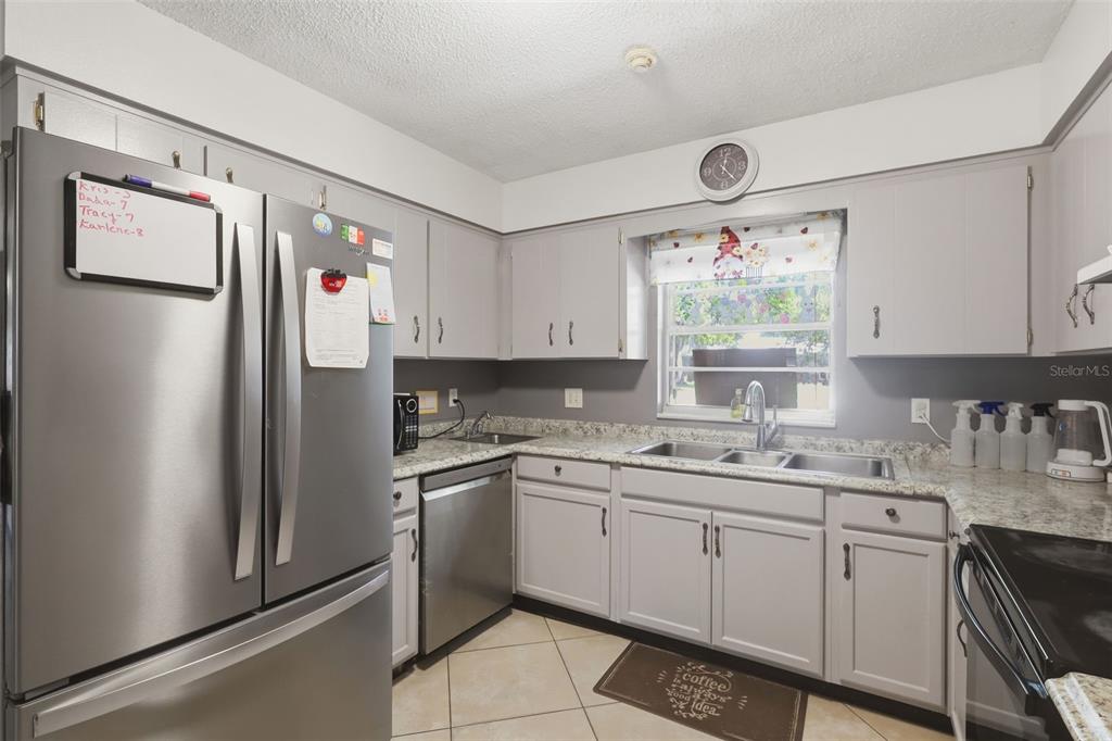 A kitchen features gray cabinets, stainless steel appliances, granite countertops, and a tile floor — 601 N PEACH STREET, BUNNELL, FL