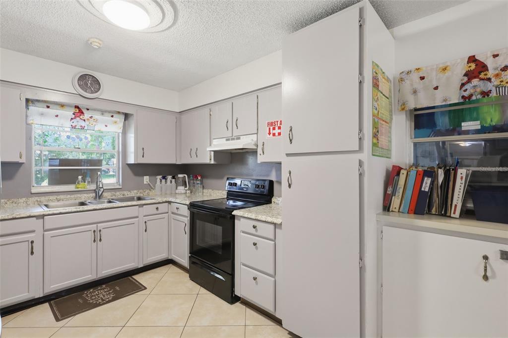 A kitchen with light gray cabinets, a black stove, and a window above the sink — 601 N PEACH STREET, BUNNELL, FL