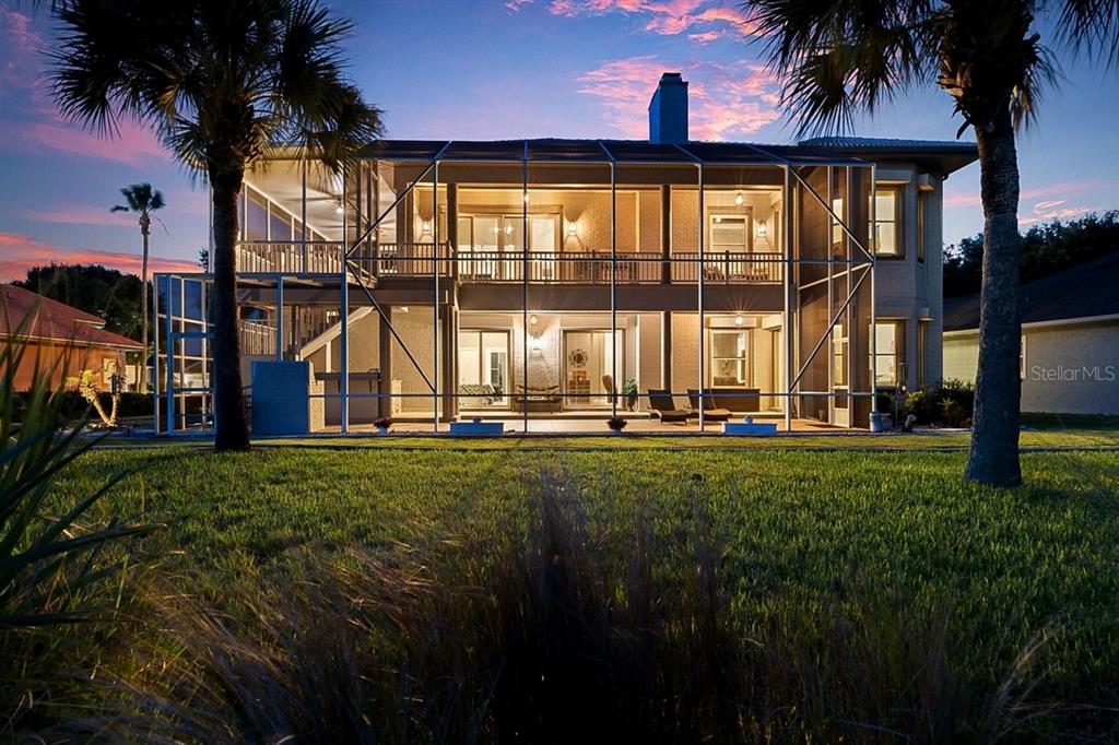 A two-story house with a screened-in porch and balcony at dusk — 92 LAGARE STREET, PALM COAST, FL
