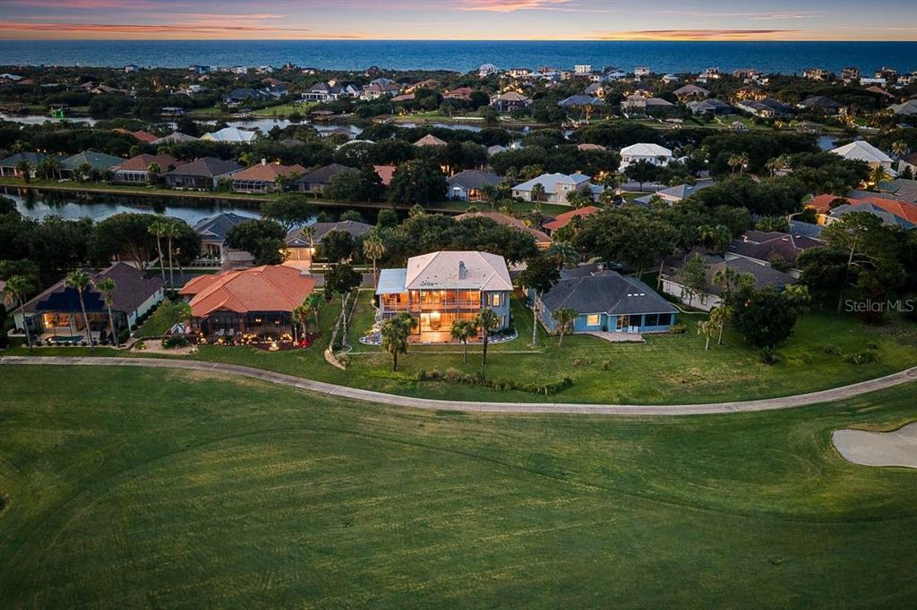 An aerial view shows a multi-story house with a lit porch overlooking a golf course — 92 LAGARE STREET, PALM COAST, FL