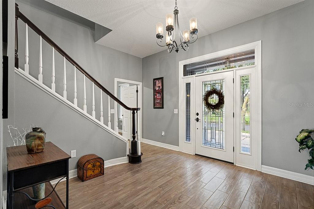 A foyer features wood-look tile flooring, a staircase with white railings, and a front door — 92 LAGARE STREET, PALM COAST, FL