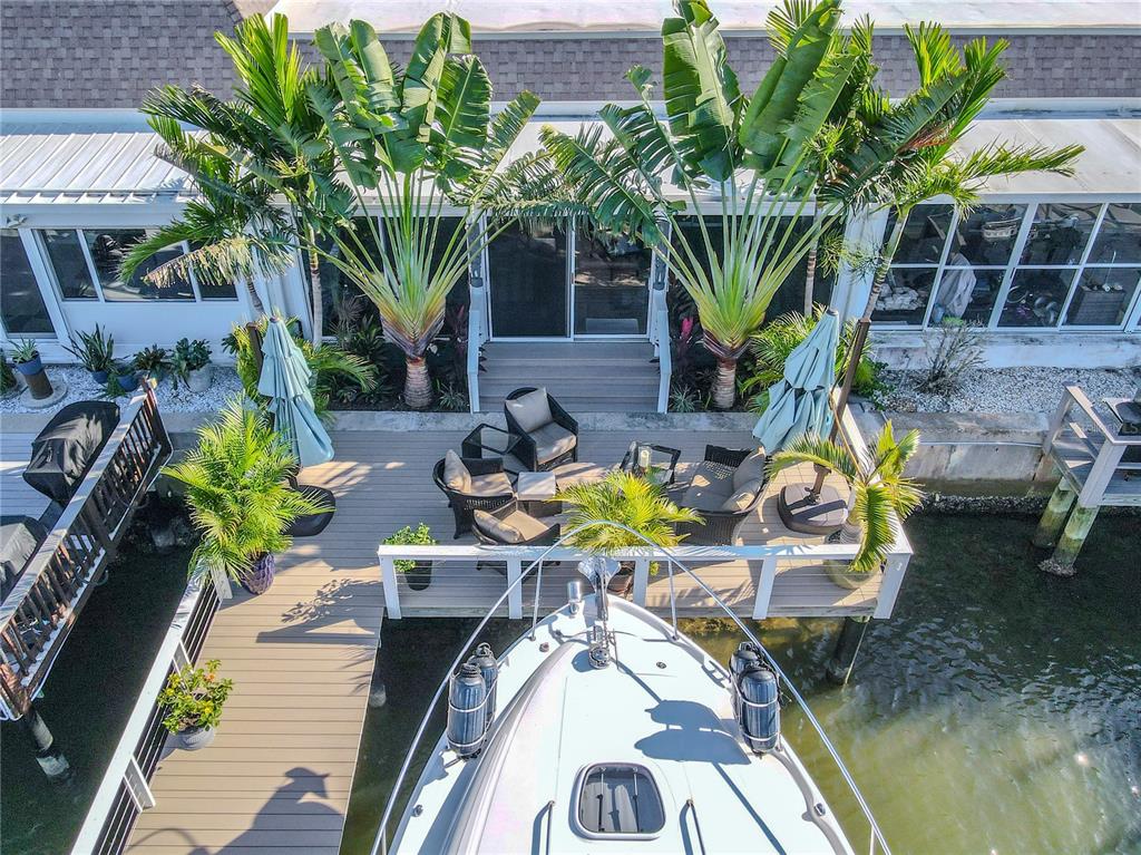 An aerial view shows a boat docked at a wooden deck with patio furniture — 345 BOCA CIEGA POINT BOULEVARD, ST PETERSBURG, FL