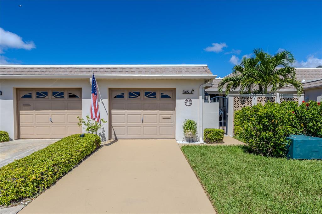 A tan single-story house exterior features two garage doors, a driveway, and a palm tree — 345 BOCA CIEGA POINT BOULEVARD, ST PETERSBURG, FL