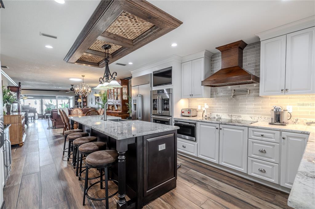 A kitchen features a dark wood island, white cabinetry, a wood range hood, and tile flooring — 345 BOCA CIEGA POINT BOULEVARD, ST PETERSBURG, FL