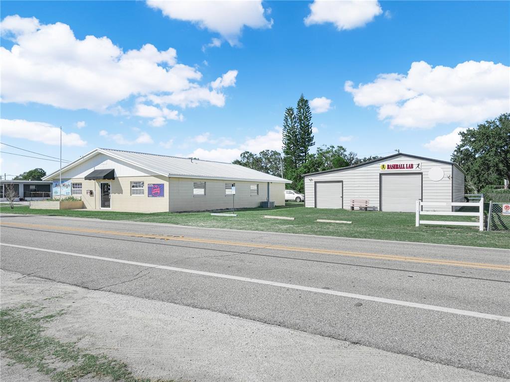 A light-colored commercial building and a separate baseball lab structure sit beside a paved road — 109 N 3RD STREET, EAGLE LAKE, FL