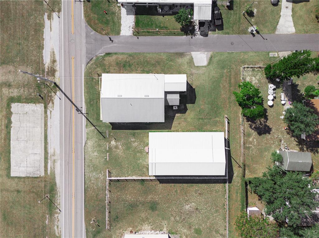 An aerial view shows two white-roofed buildings on a grassy lot next to a road — 109 N 3RD STREET, EAGLE LAKE, FL