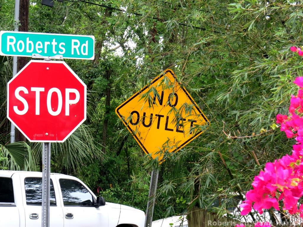 A stop sign and a no outlet sign are mounted on a pole near trees — ROBERTS ROAD, PALM HARBOR, FL