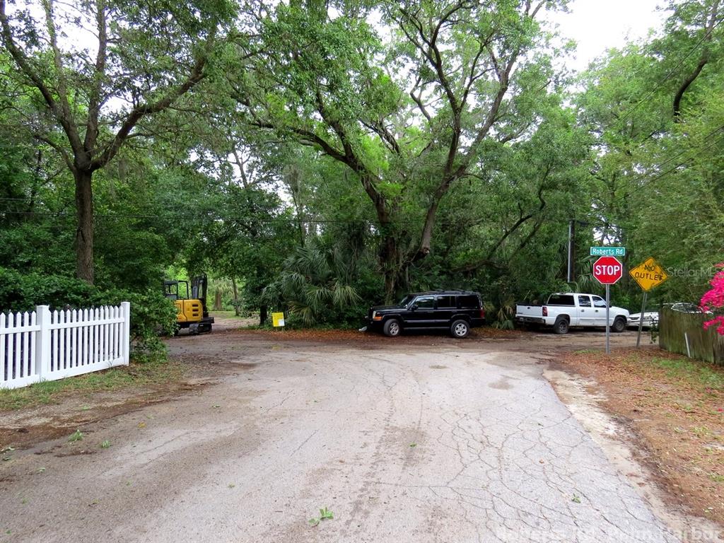 A paved road leads to a stop sign, a black SUV, and a white pickup truck — ROBERTS ROAD, PALM HARBOR, FL