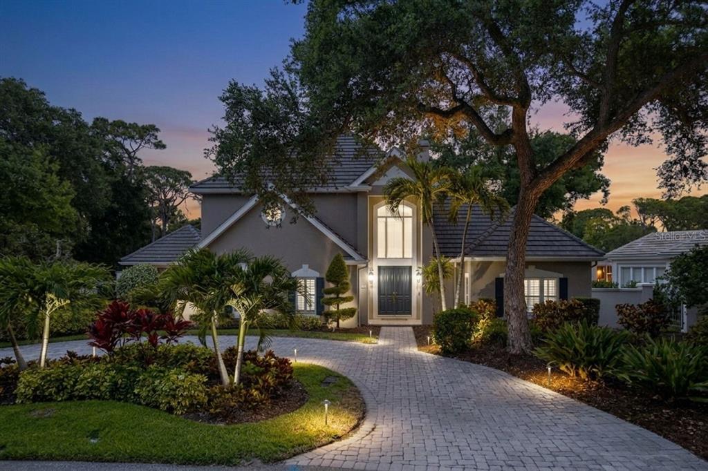 A two-story house with a paved driveway, palm trees, and a large arched window — 97 SUGAR MILL DRIVE, OSPREY, FL