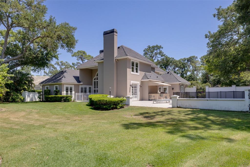 A two-story house with a gray exterior, a large chimney, and a backyard patio area — 97 SUGAR MILL DRIVE, OSPREY, FL