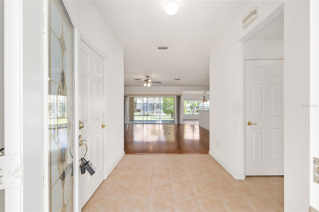 A tiled entryway leads into a living area with hardwood floors and large sliding doors — 9210 SE 118TH LOOP, SUMMERFIELD, FL