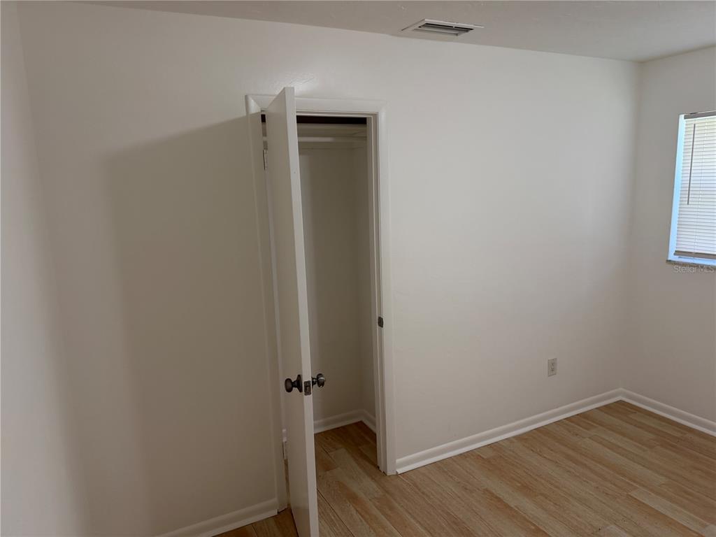 A bedroom with white walls, light wood-look flooring, and an open closet — 2185 NW 3RD STREET, OKEECHOBEE, FL